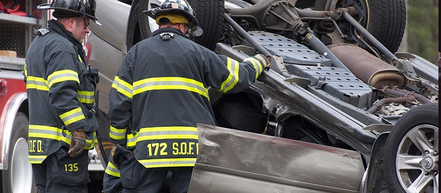 Firefighters inspecting flipped vehicle from accident