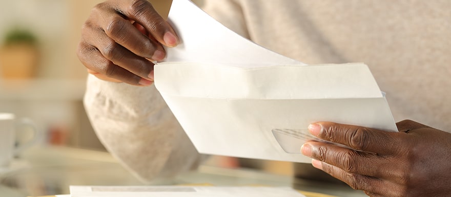 Person opening lawsuit settlement check envelope