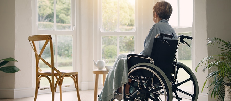 Elderly person sitting in wheelchair alone in room near window