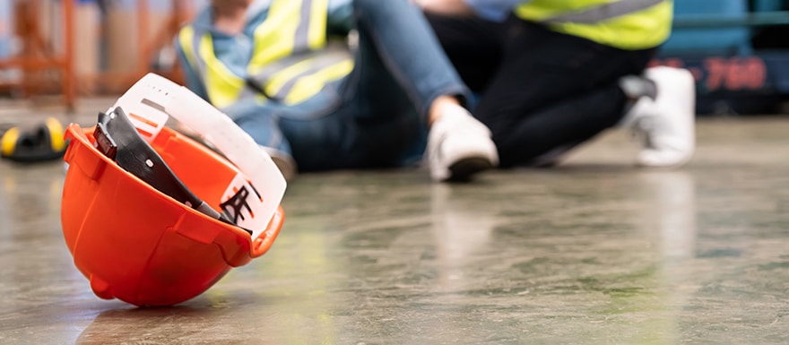 warehouse worker injured on the ground with helmet on the floor next to them